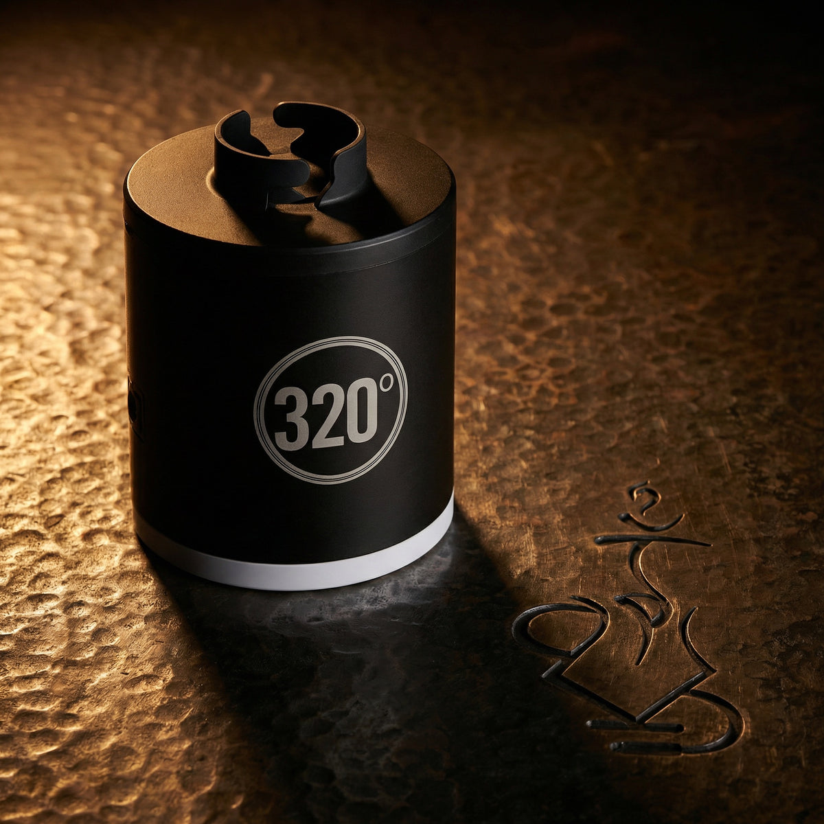 320° LED electric coal starter pump lit dramatically on a warm hammered bronze surface, showcasing the matte black cylindrical body and circular 320° badge in a dark editorial hero shot., image 2 of 12