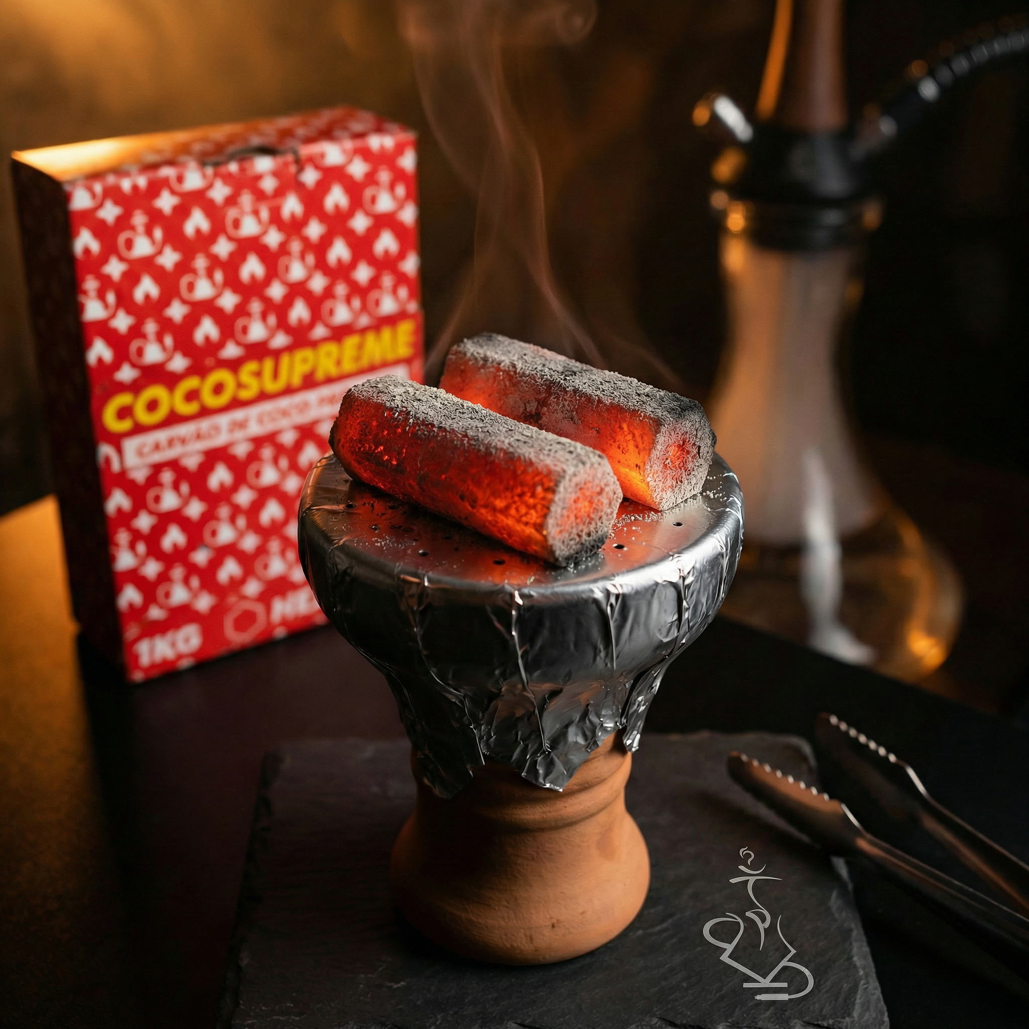 Two smoking briquettes on a wooden stand with a red box labeled 'Cocos Supreme' in the background.