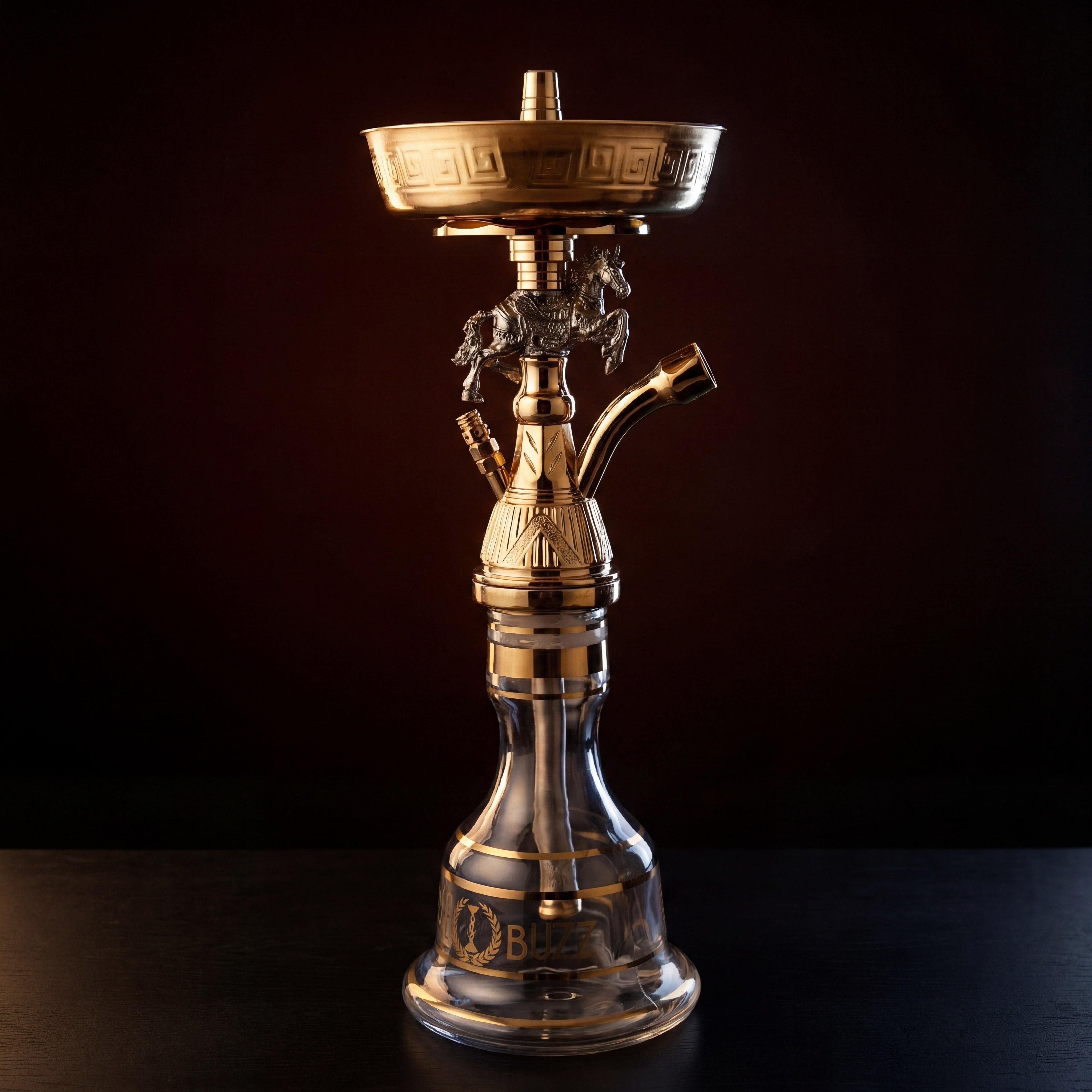 Basha Buzz Mustang gold-finish shisha pipe with rearing stallion centrepiece lit against warm dark backdrop