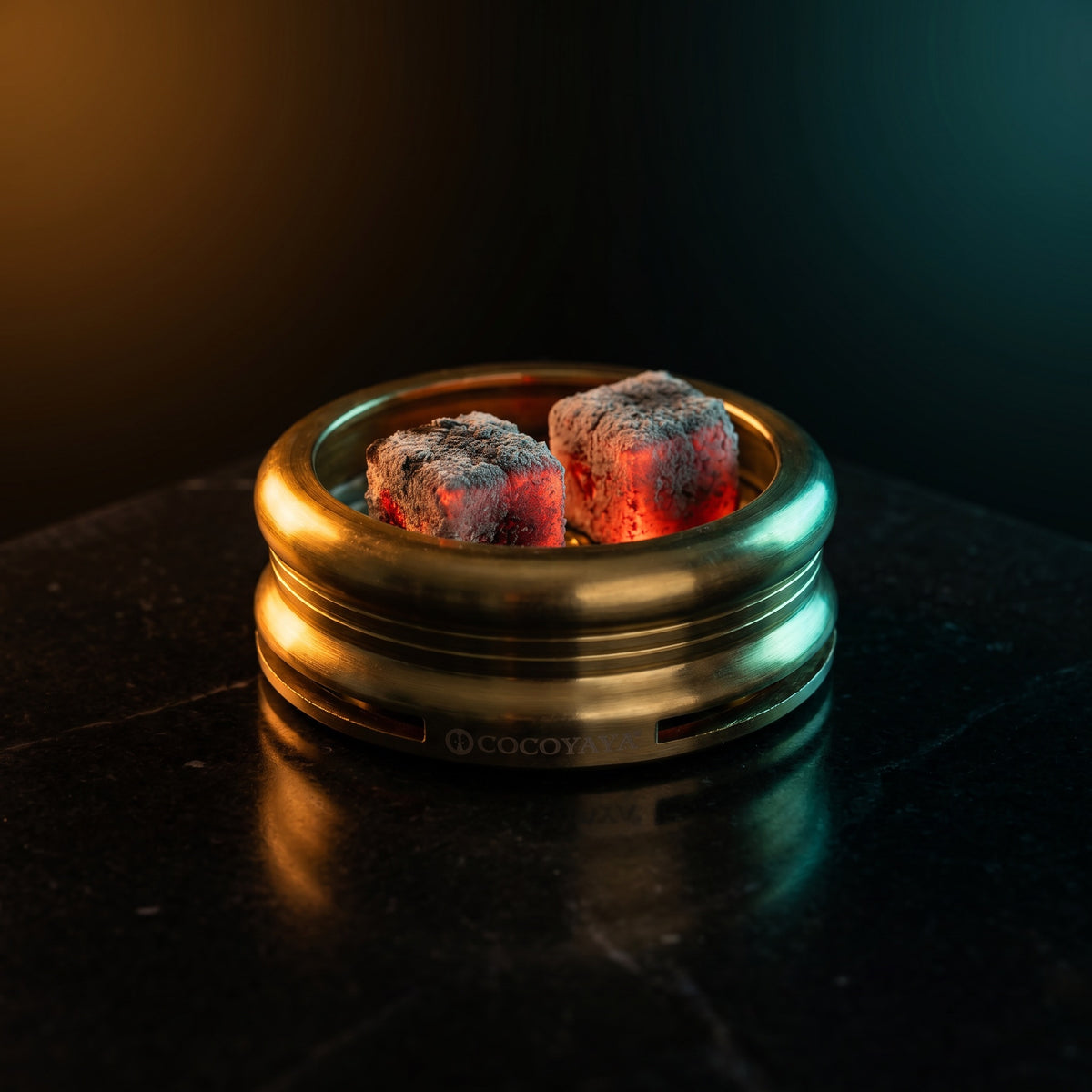 Cocoyaya Pro 5 with two lit coconut coals on heat plate, ash forming, brushed gold body on polished dark stone, image 4 of 5