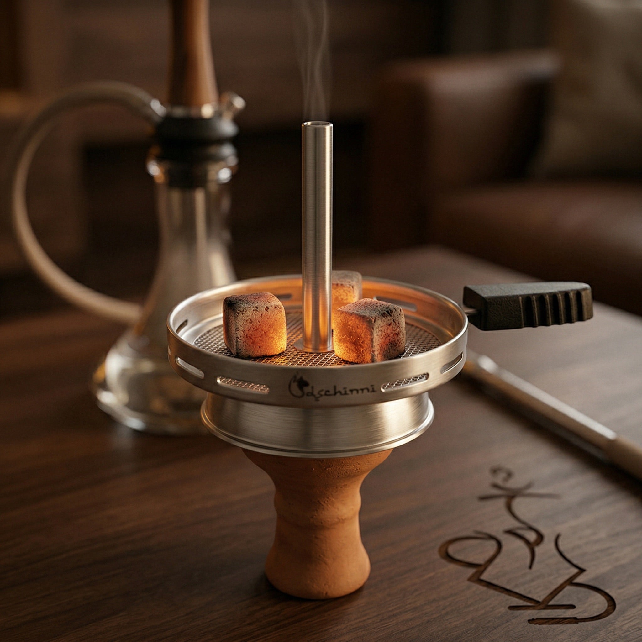 Dschinni Vulcan Air 2.0 chimney hot screen in use on a hookah bowl with glowing natural coconut charcoal on the mesh grate, warm session lighting on a dark walnut surface