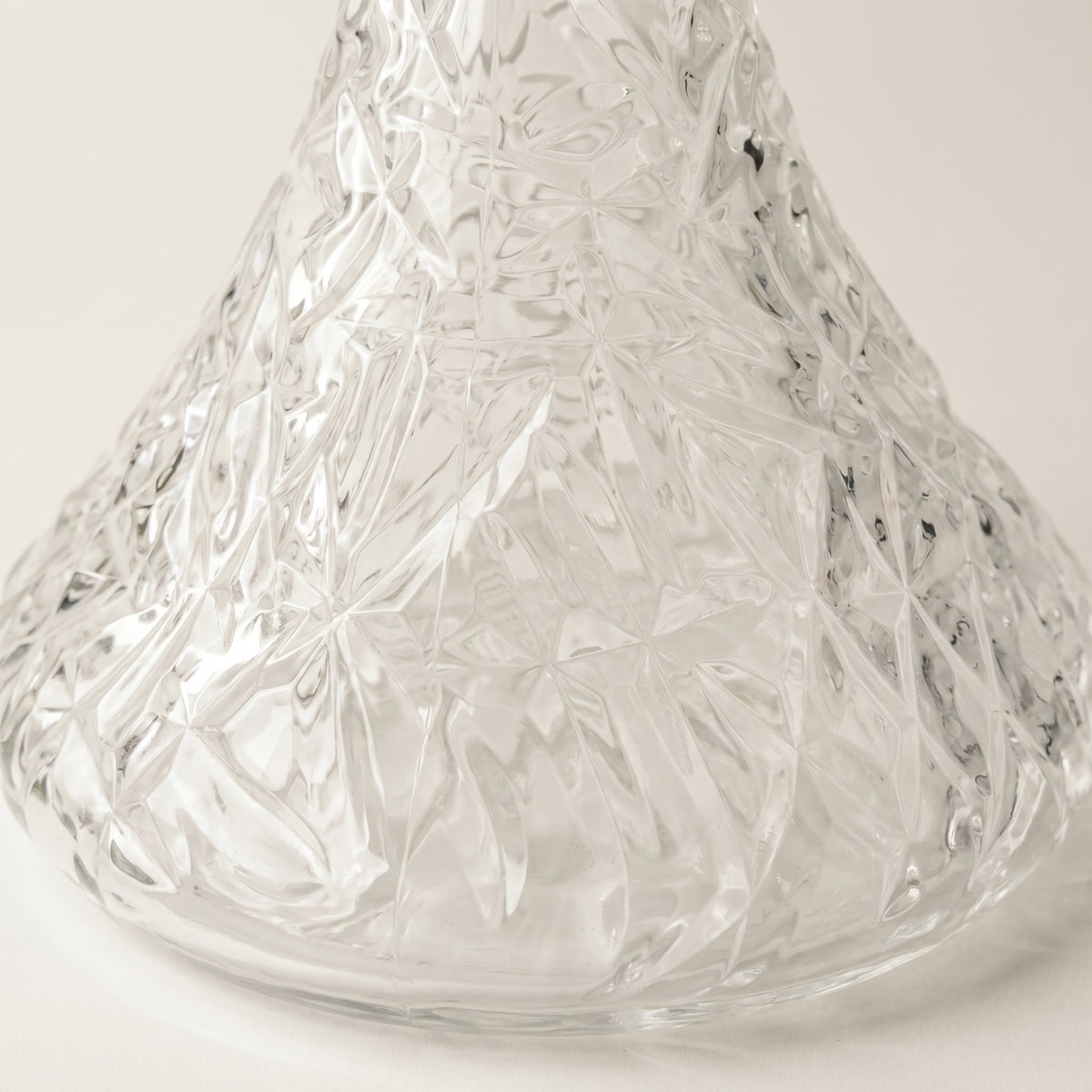 Essentials Crystal-Cut Clear Russian shisha vase on travertine plinth, refracted light fanning across the wall behind, image 4 of 4