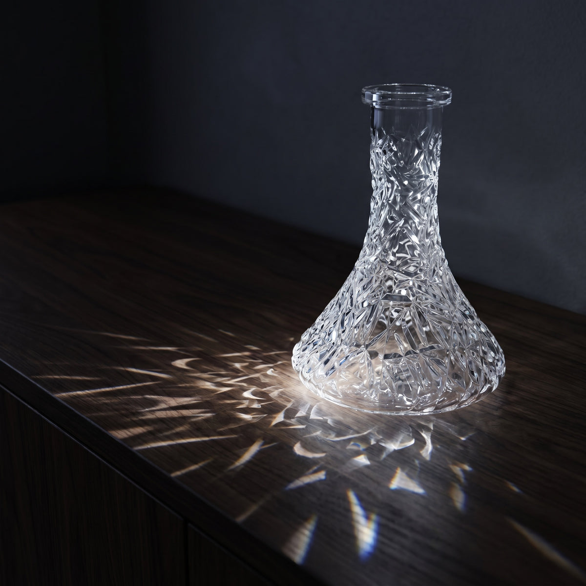 Essentials Crystal-Cut Clear Russian shisha vase on dark walnut credenza, light refracting through the cut pattern across the surface, image 2 of 4