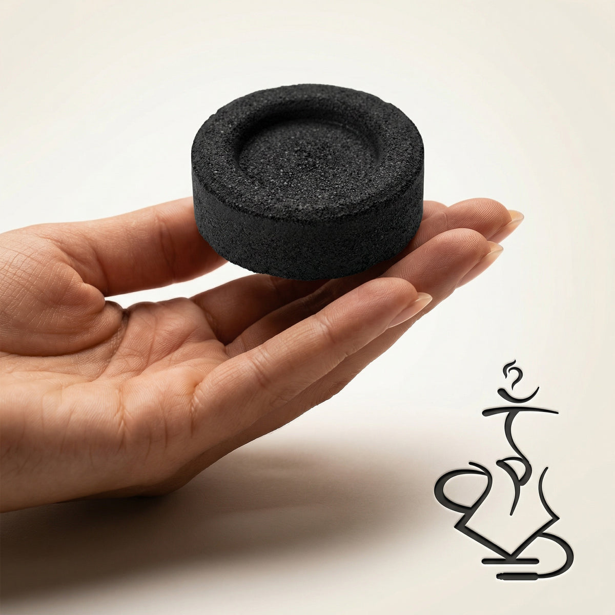 Essentials Quick-Light Charcoal 33mm tablet held flat on fingertips showing real-world size for hookah bowls and bakhoor burners on a warm studio background., image 3 of 11