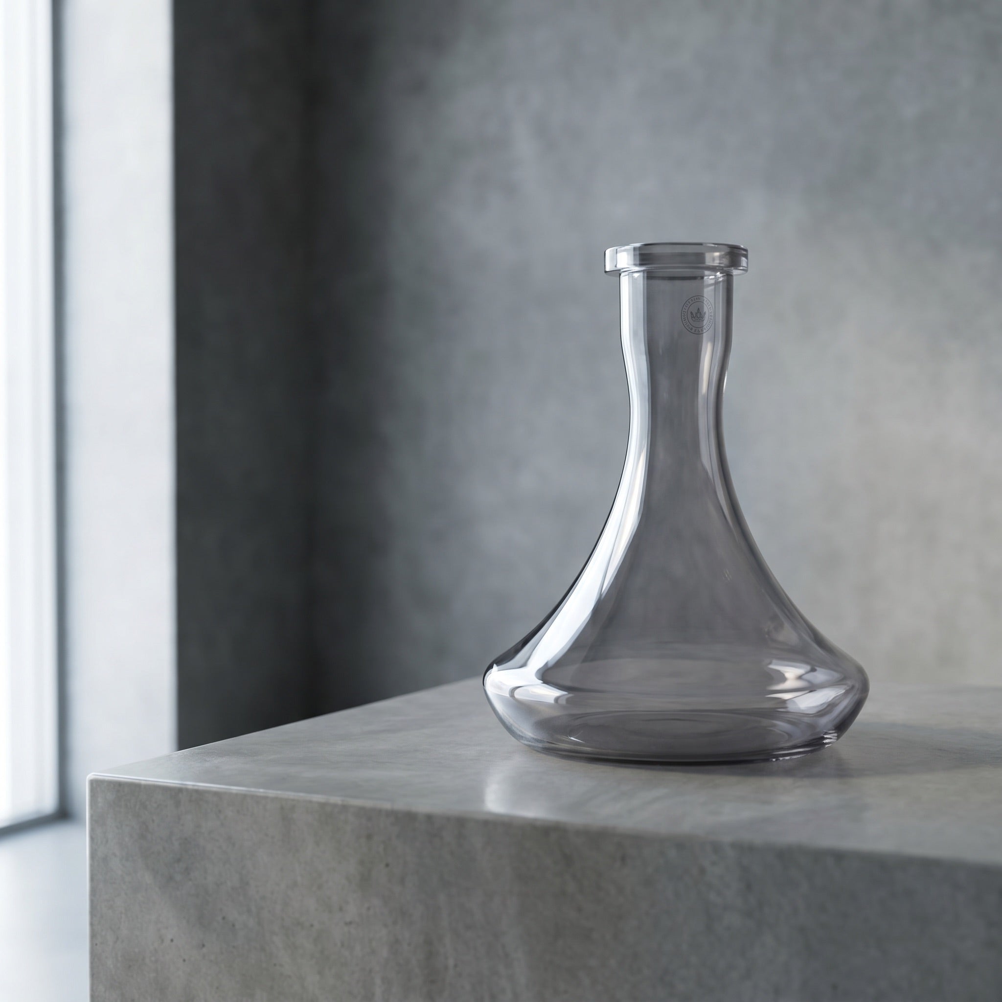 Essentials Smoke shisha vase on polished concrete plinth, smoked graphite glass transmitting daylight