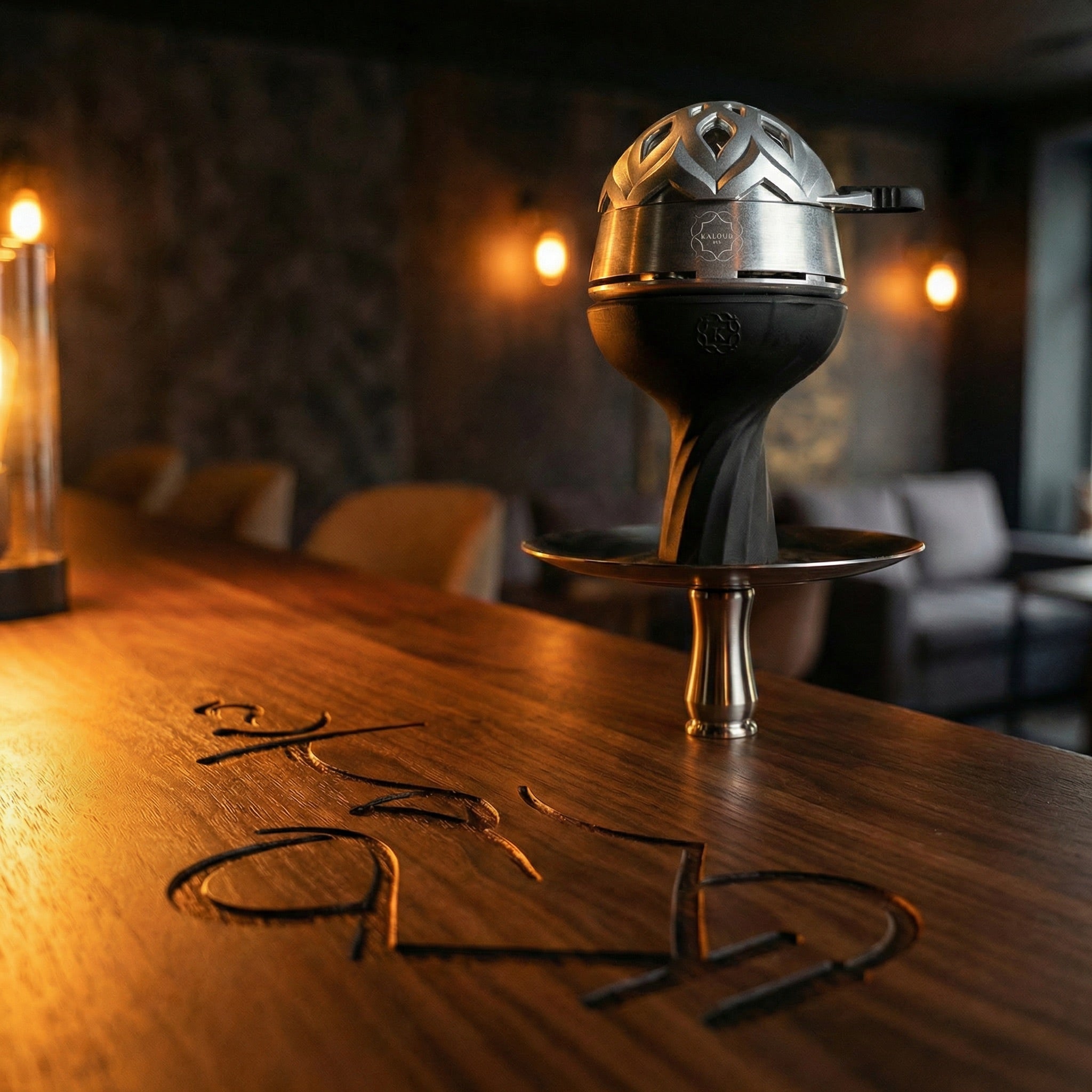 Kaloud Lotus I+3 Argis Silver HMD mounted on a premium hookah in a warm lounge setting, styled as an aspirational session centrepiece on a walnut bar top.