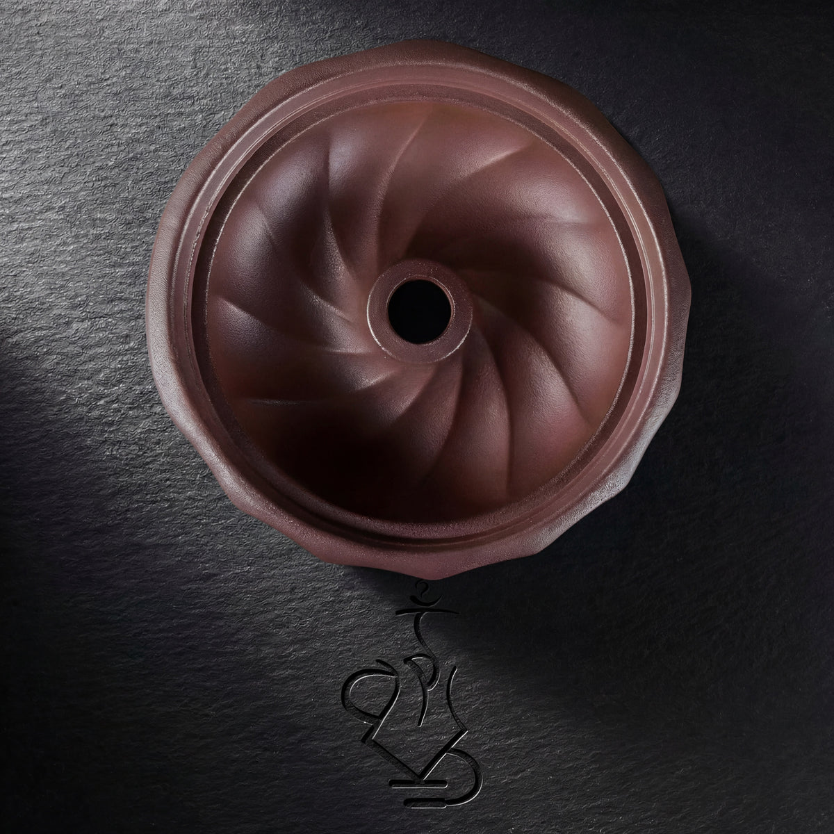 Overhead view of the Kaloud Samsaris Kore Qì Short red clay bowl interior showing spiralling phunnel channels and central spire hole, image 10 of 17