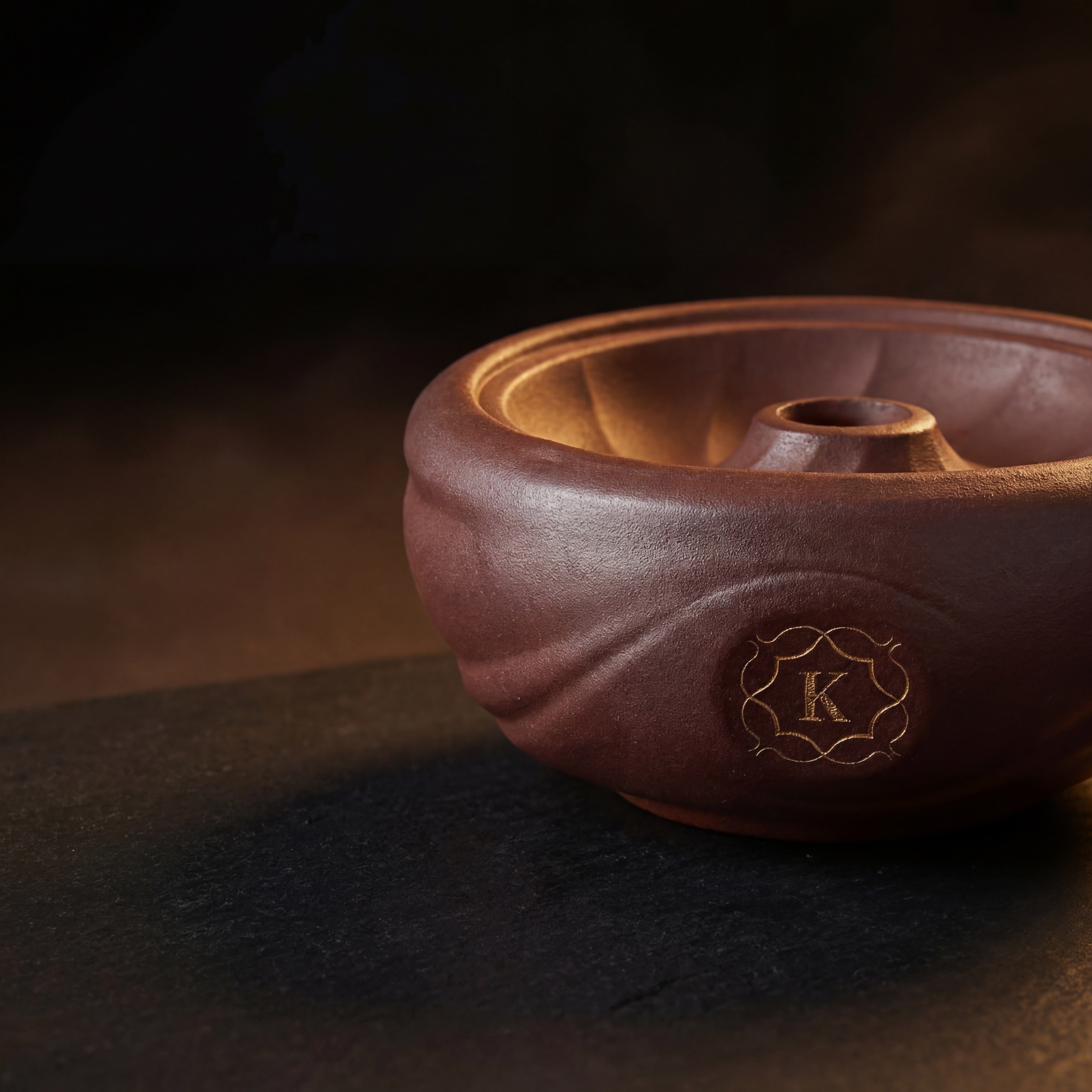 Kaloud Kore Qì Short red clay phunnel bowl on dark basalt with warm raking light, gold cartouche detail
