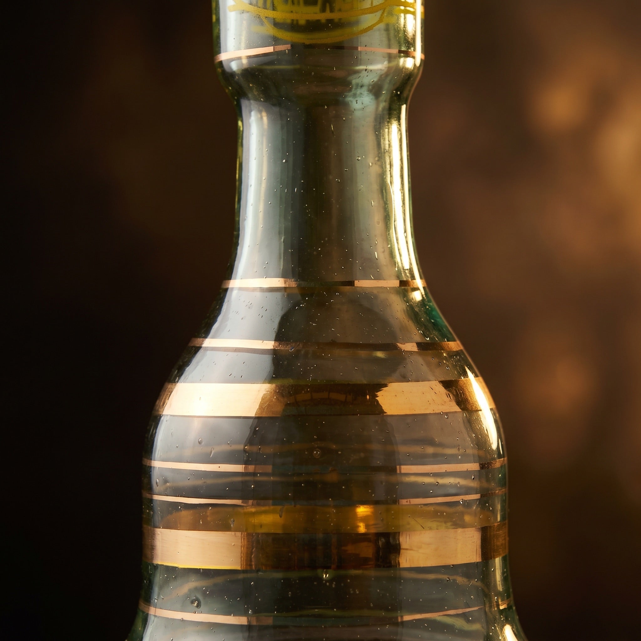 Macro detail of hand-applied gold bands and seed bubbles on the Khalil Mamoon 30 cm hand-blown glass base
