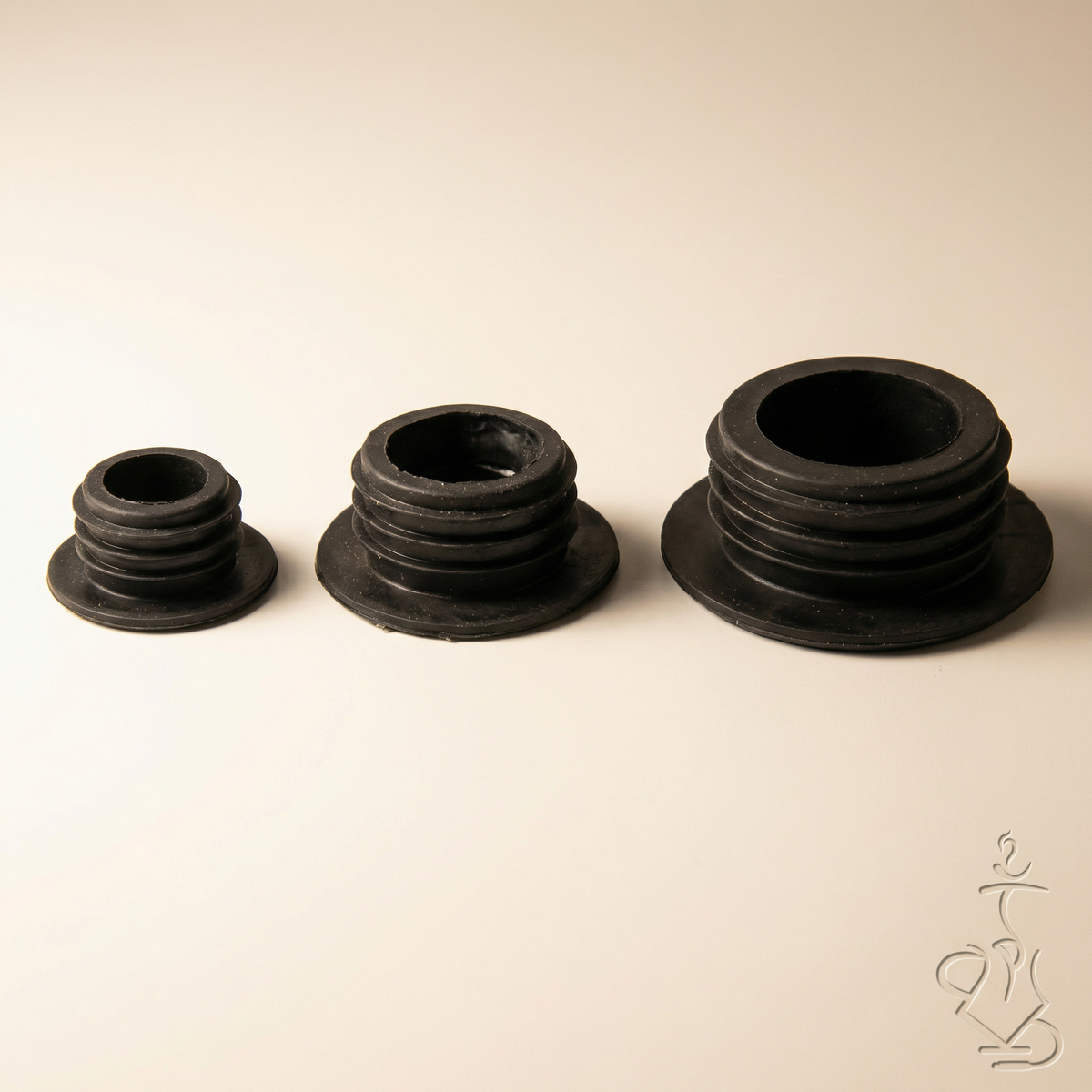 Three Khalil Mamoon black rubber base grommets in small, medium, and large sizes arranged side by side on a white studio background, showing the stepped-ring profile and size progression, image 2 of 10