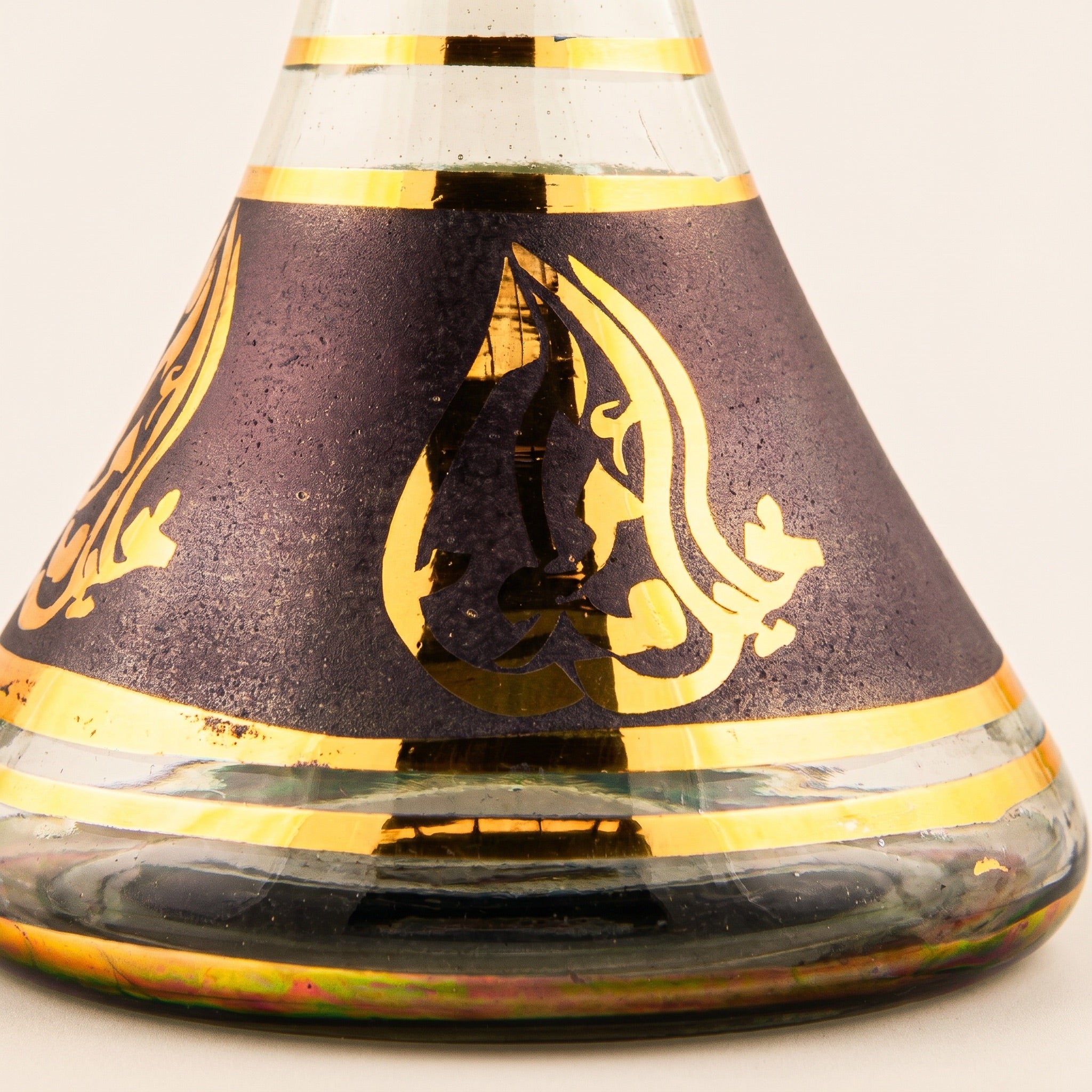 Macro detail of Khalil Mamoon black and gold base showing hand-painted gold calligraphy on matte panel