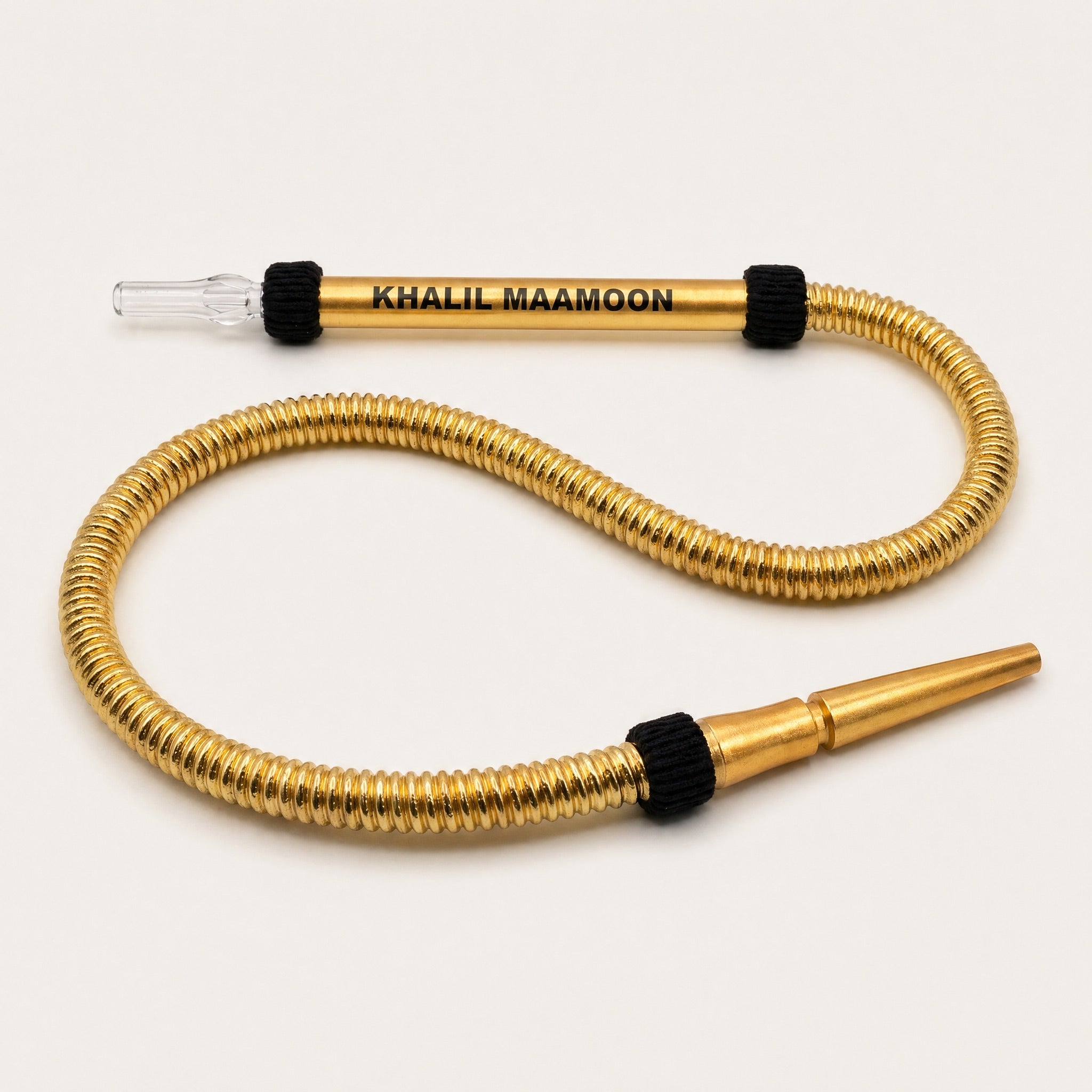 Khalil Mamoon Gold Washable Hose laid in S-curve on white studio sweep, acrylic mouthpiece and gold tubing