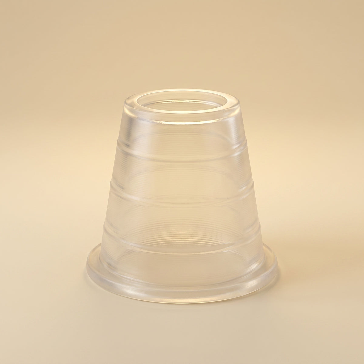 Khalil Mamoon hose grommet, translucent rubber with ridged body and flanged base, on warm cream studio background, image 2 of 7