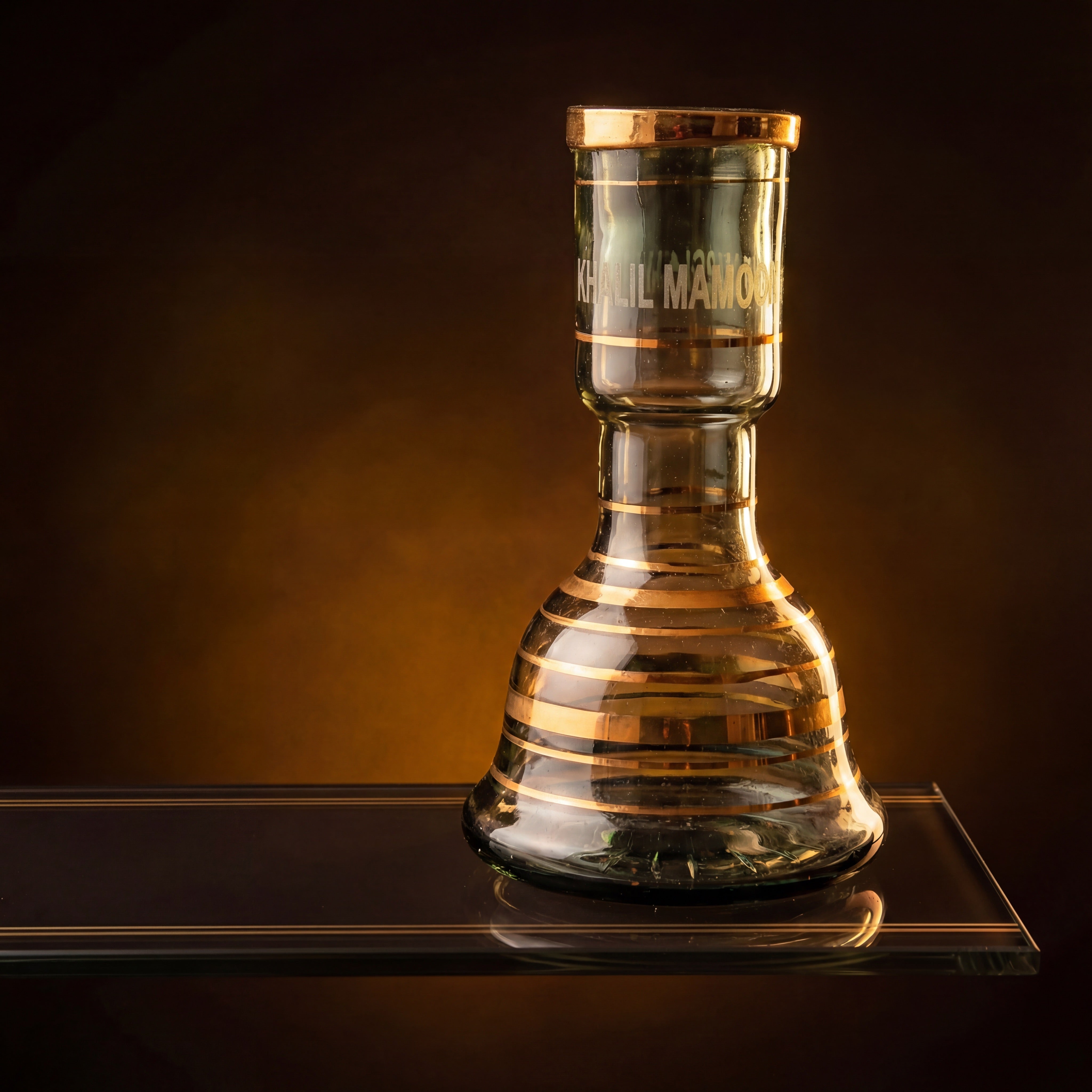 Khalil Mamoon Mini Beast gold stripe base glowing under warm amber light on reflective plinth — The Premium Way
