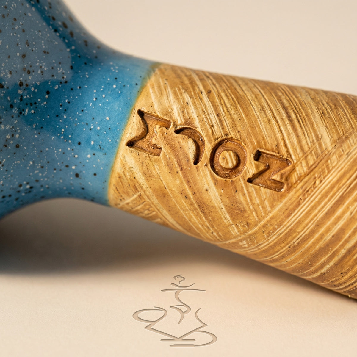 Macro detail of the Moon Phunnel showing the speckled blue glaze meeting raw tan clay and the hand-stamped MOON wordmark pressed into the wheel-thrown surface., image 7 of 11