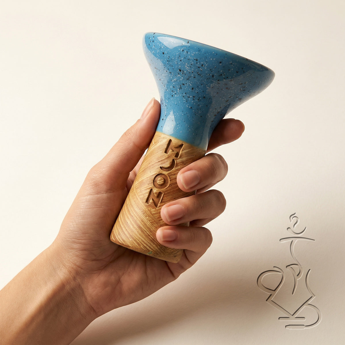 Moon Phunnel blue glazed clay bowl held in a hand showing its compact palm-scale size, fingers gripping the raw tan clay base beneath the speckled blue glaze., image 6 of 11