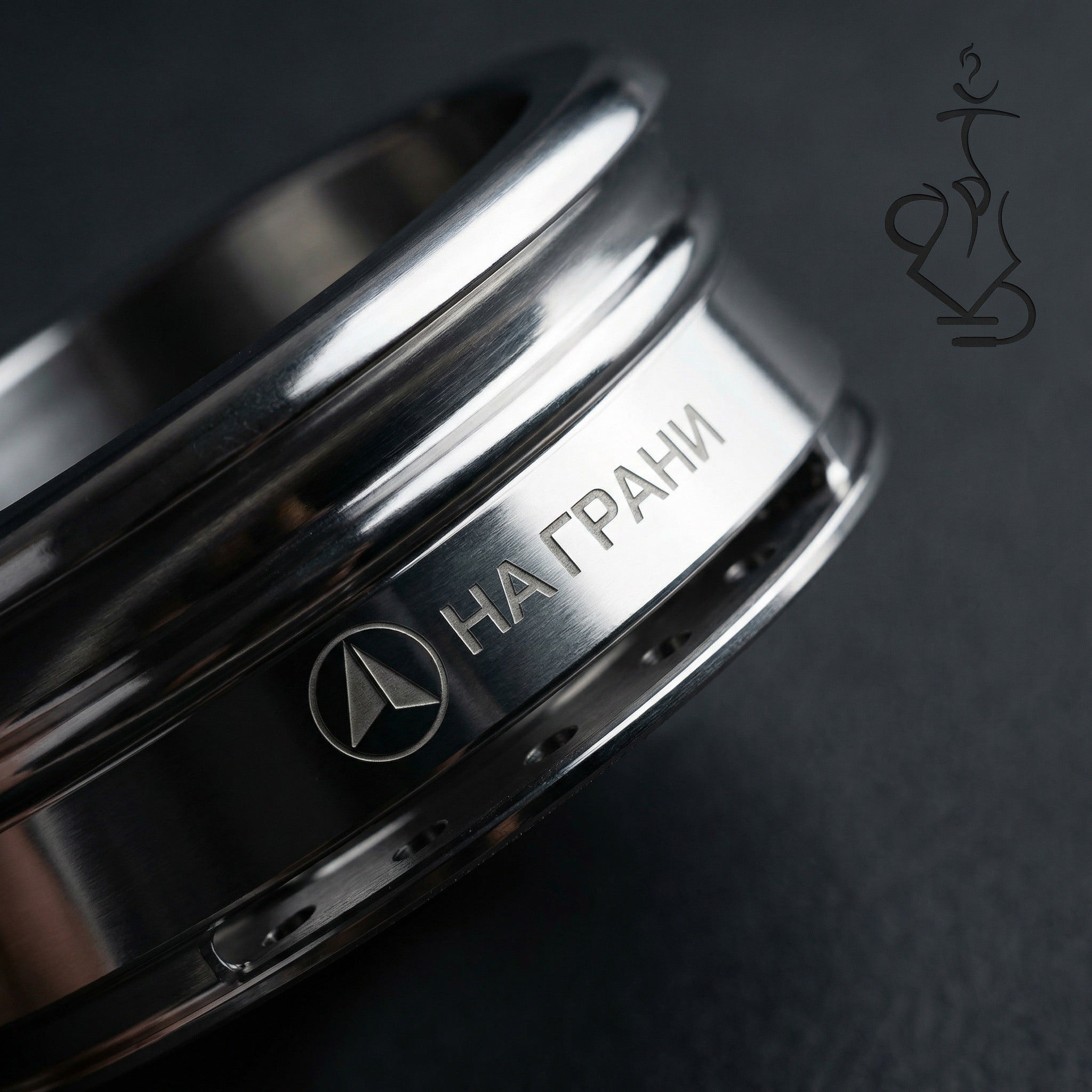Close-up macro detail of the На Грани logo engraving on the polished stainless steel band of the On The Edge HMD, dramatic lighting on dark surface