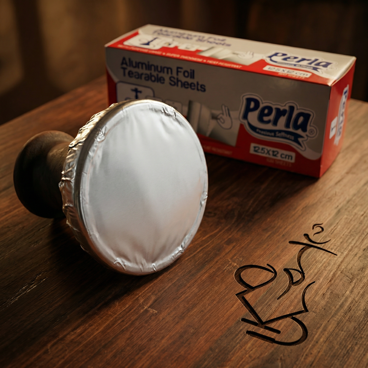 Perla Heavy-Duty Shisha Foil sheet stretched tightly over the rim of a standard clay phunnel hookah bowl, ready for hole-poking, with the dispenser box visible behind., image 2 of 2