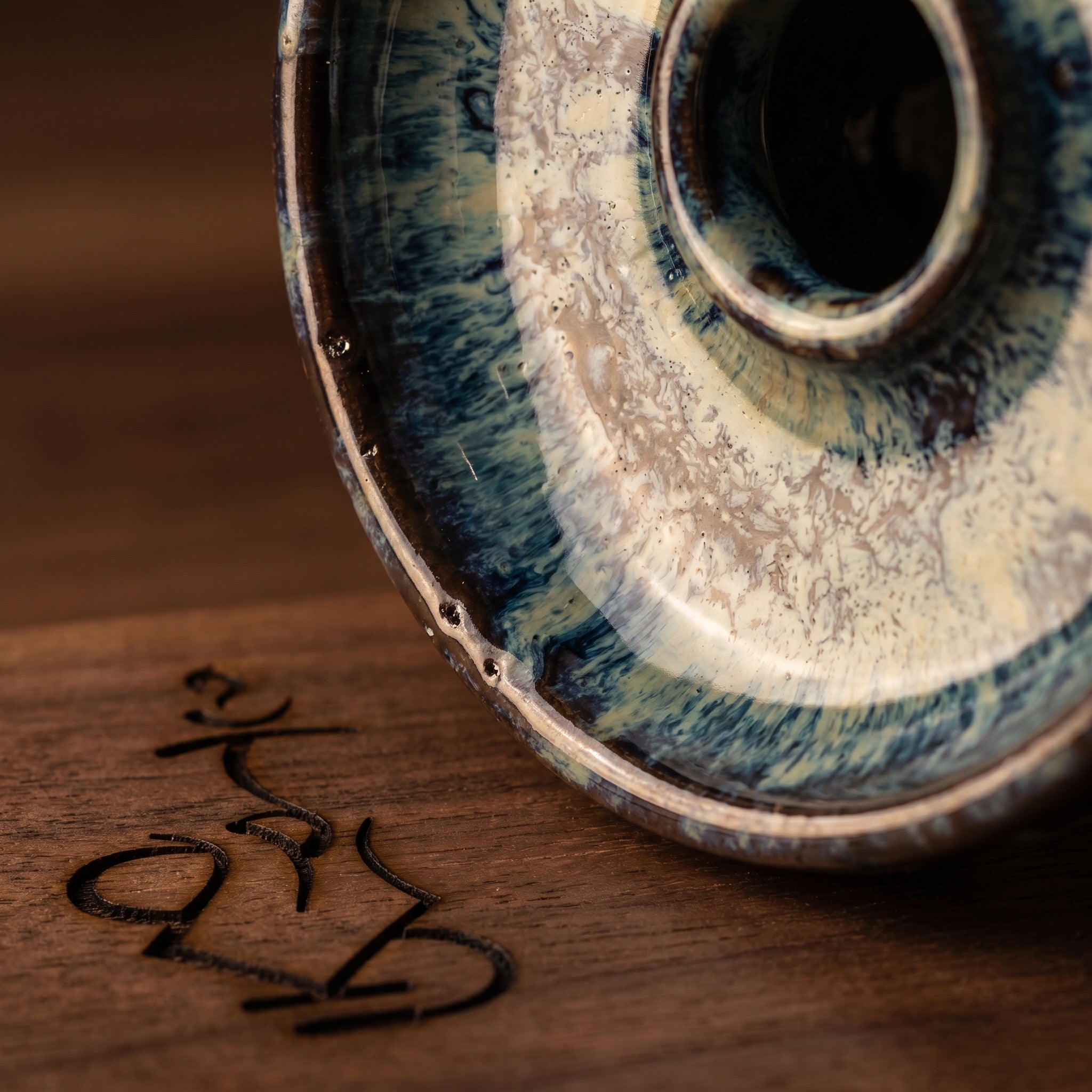 Macro close-up of the Queen phunnel Frozen reactive glaze — blue-teal drip and cream mottling on ceramic, The Premium Way.