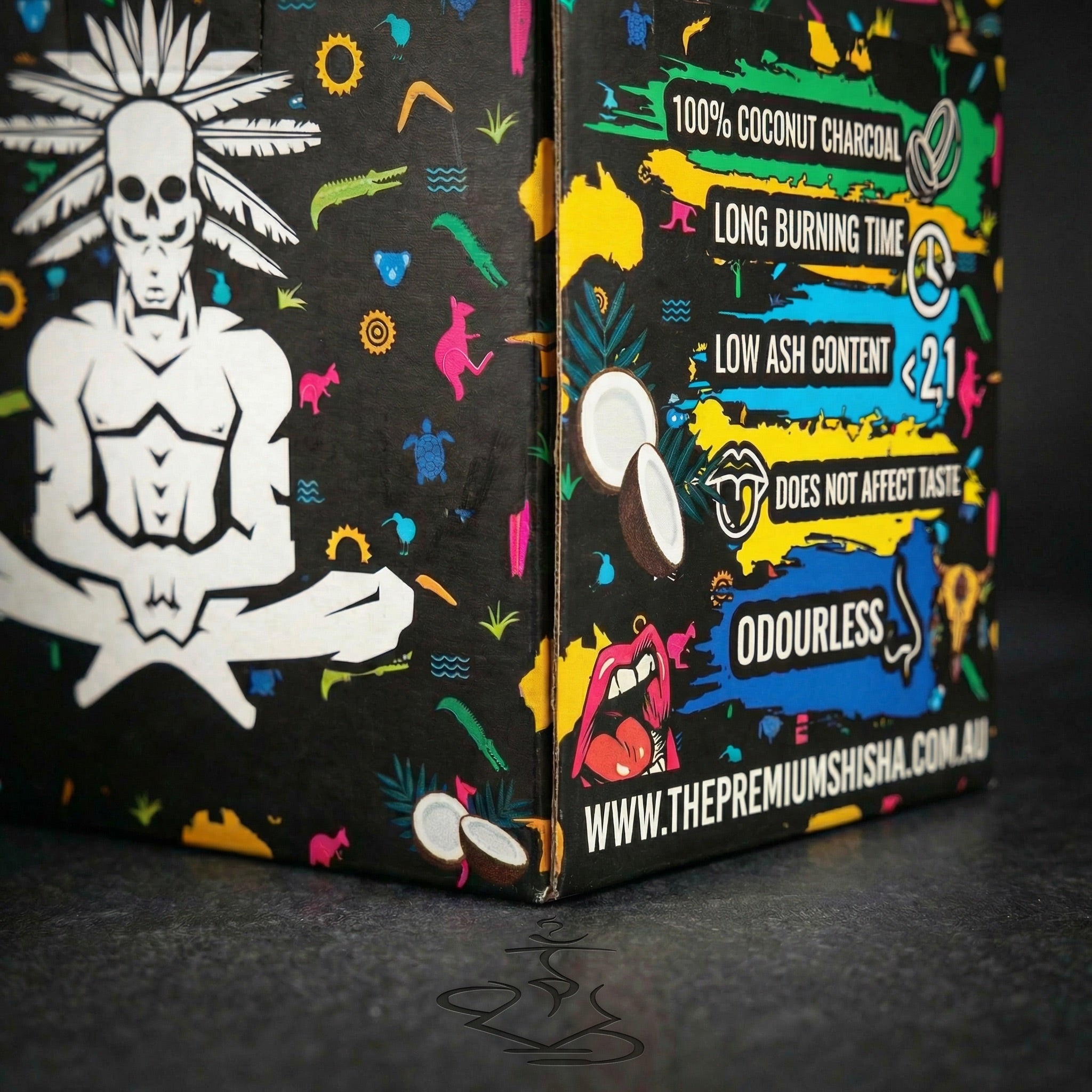 Close-up detail of Shaman 26mm coconut charcoal 1kg box corner showing the seated skull mascot meeting the colourful features panel with product claims.