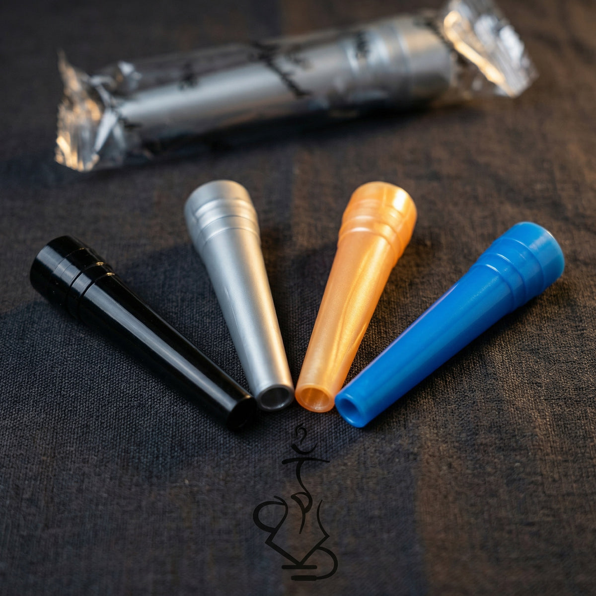 Close-up detail of four ShishaDoc disposable hookah mouth tips in blue, black, silver, and orange arranged in a fan with wrapped tip showing individual packaging, image 4 of 18