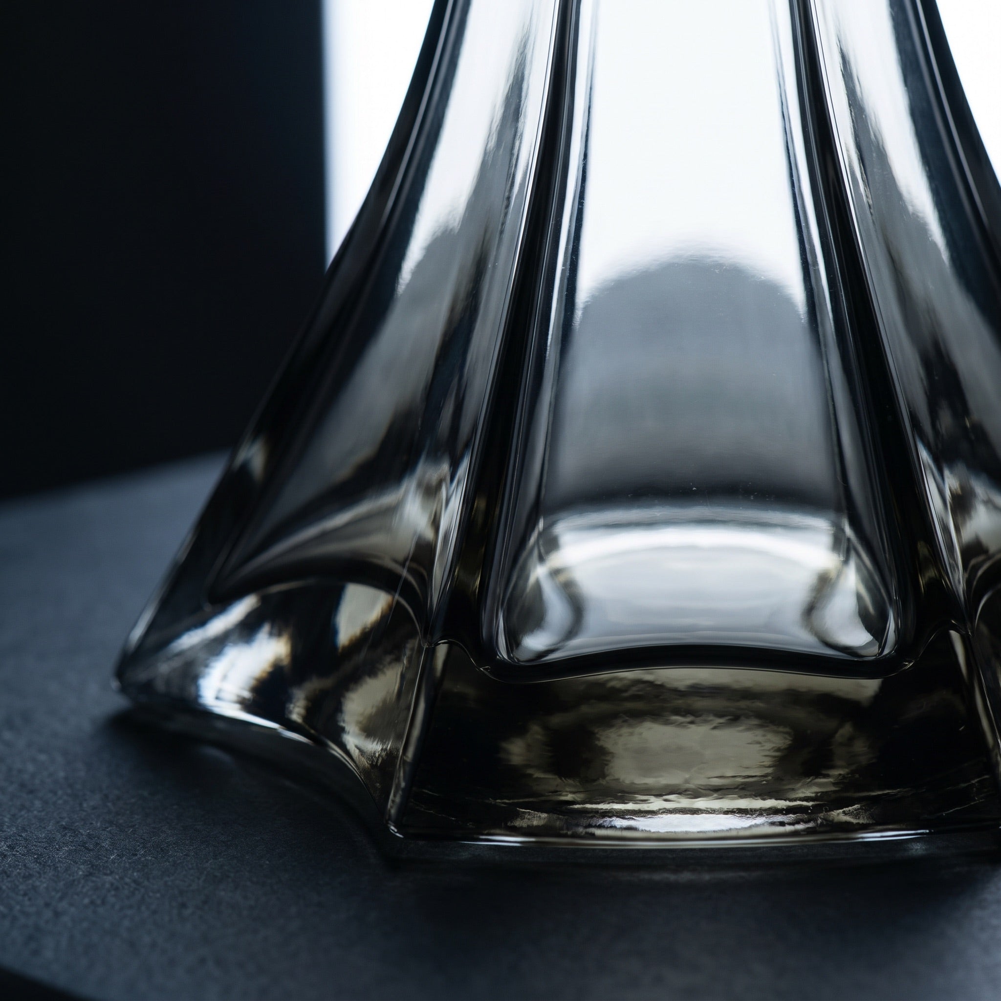 Close-up of the Starlight hookah base showing faceted cut-glass ridges, smoky black tint deepening at panel junctions, and thick hand-blown glass at the star footprint