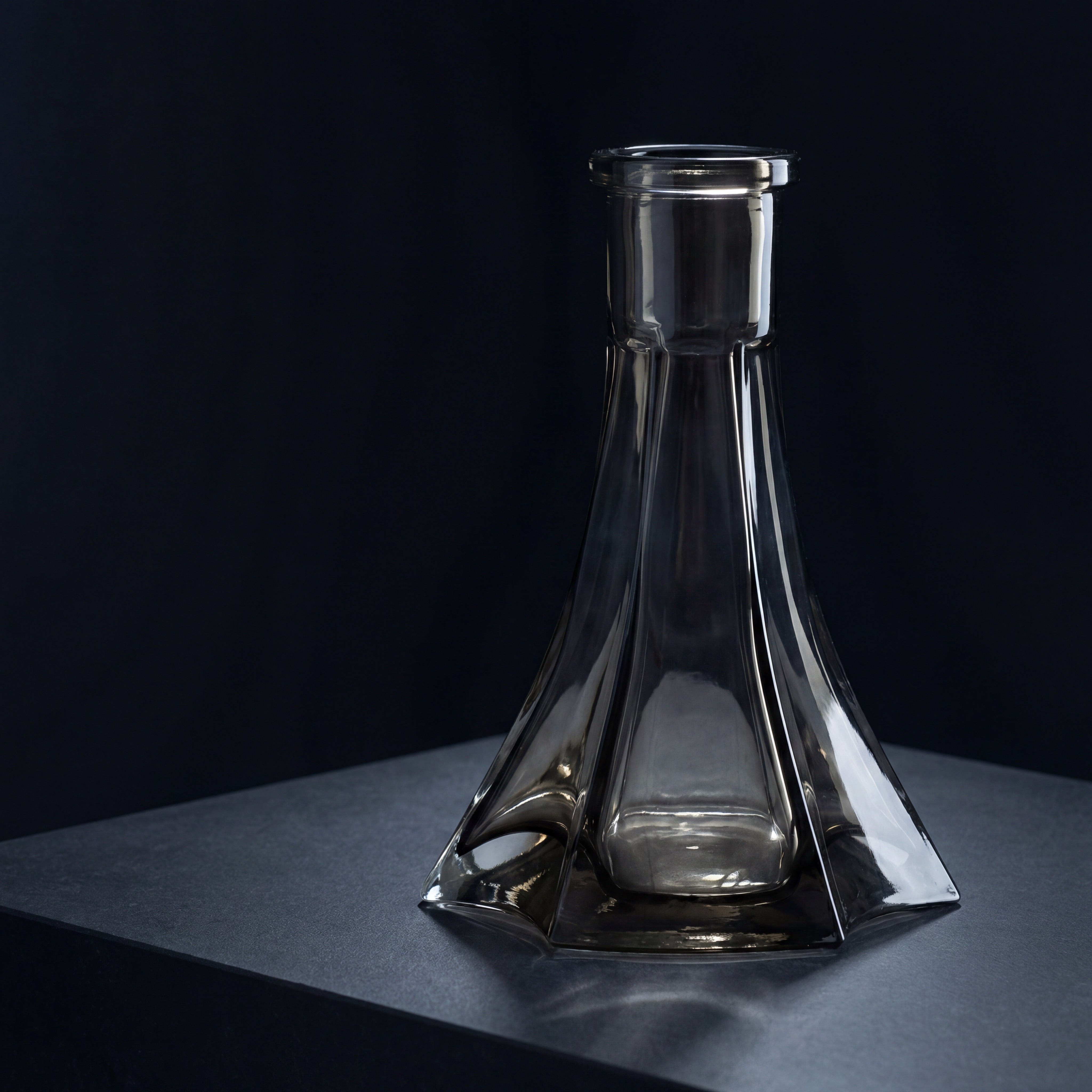 Starlight black tint hookah base on a dark stone plinth, light refracting through faceted smoky glass panels in a modernist gallery setting