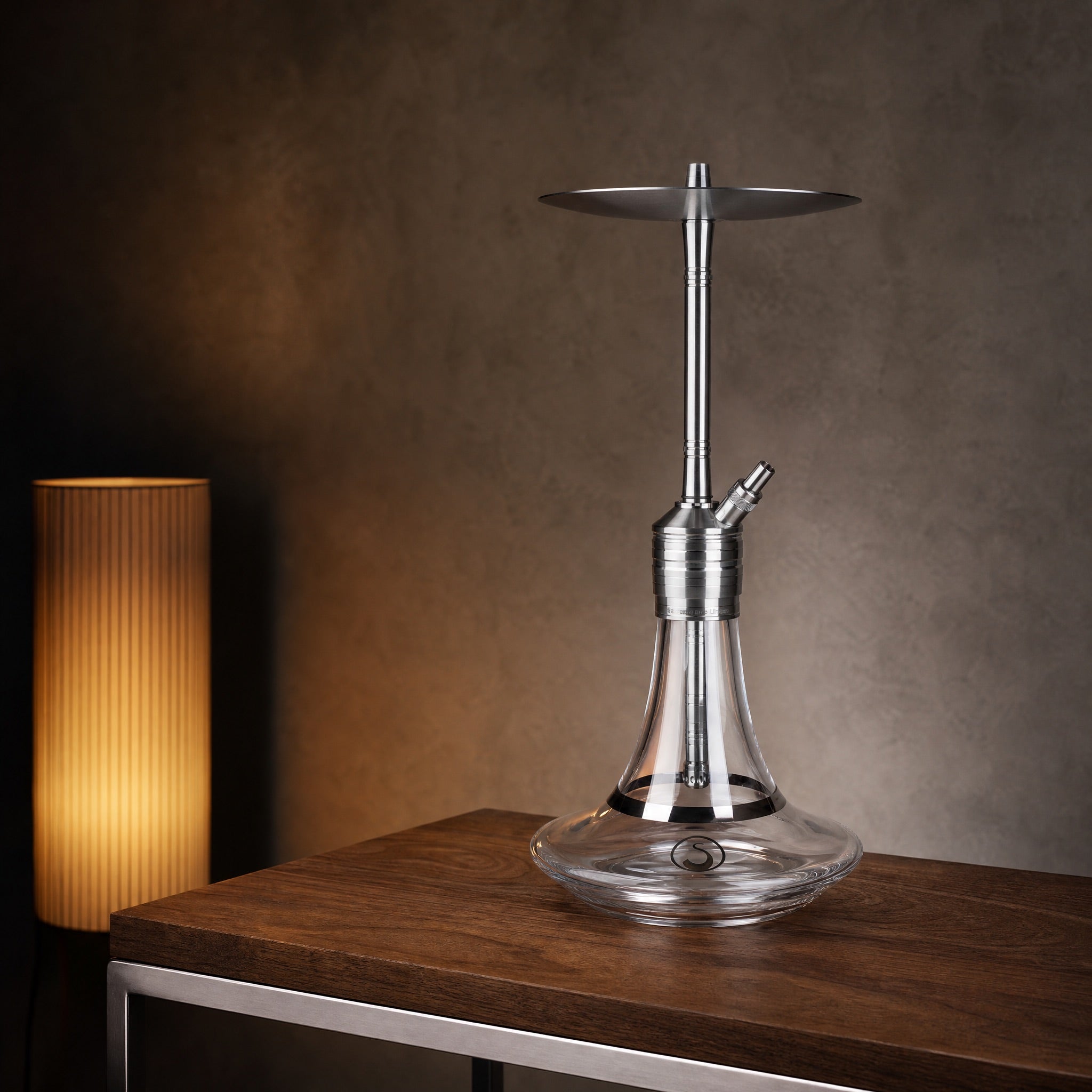 Steamulation Ultimate One Gen II clear shisha pipe on walnut side table in modernist interior at dusk