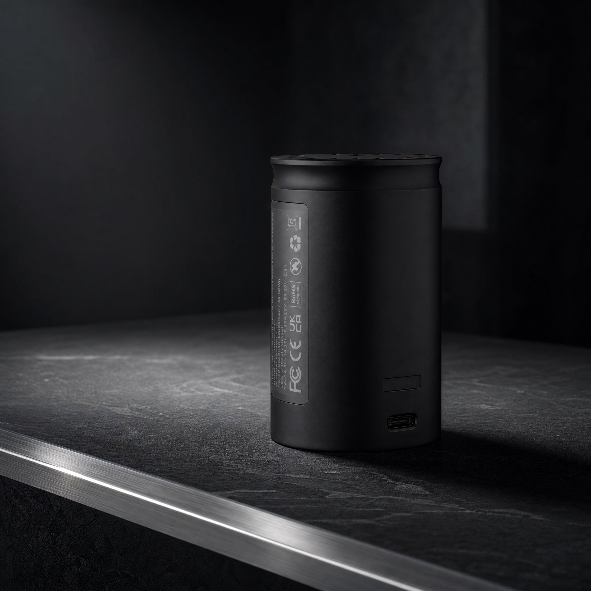 XKAH Pro replacement battery on dark stone, USB-C port visible, precision-instrument lighting.